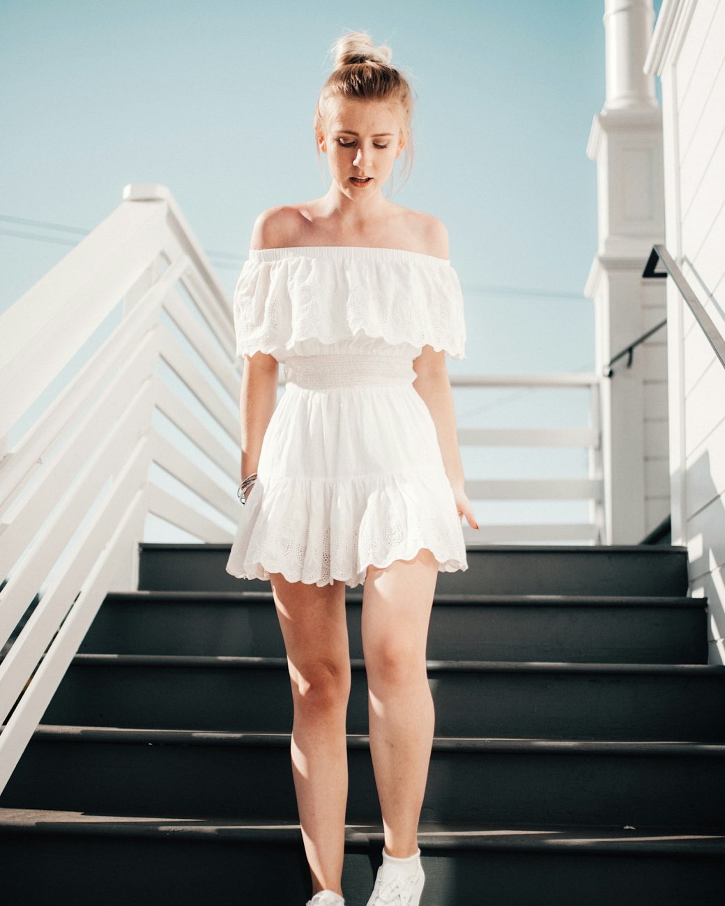 Frau in einem weißen Sommerkleid auf einer Treppe